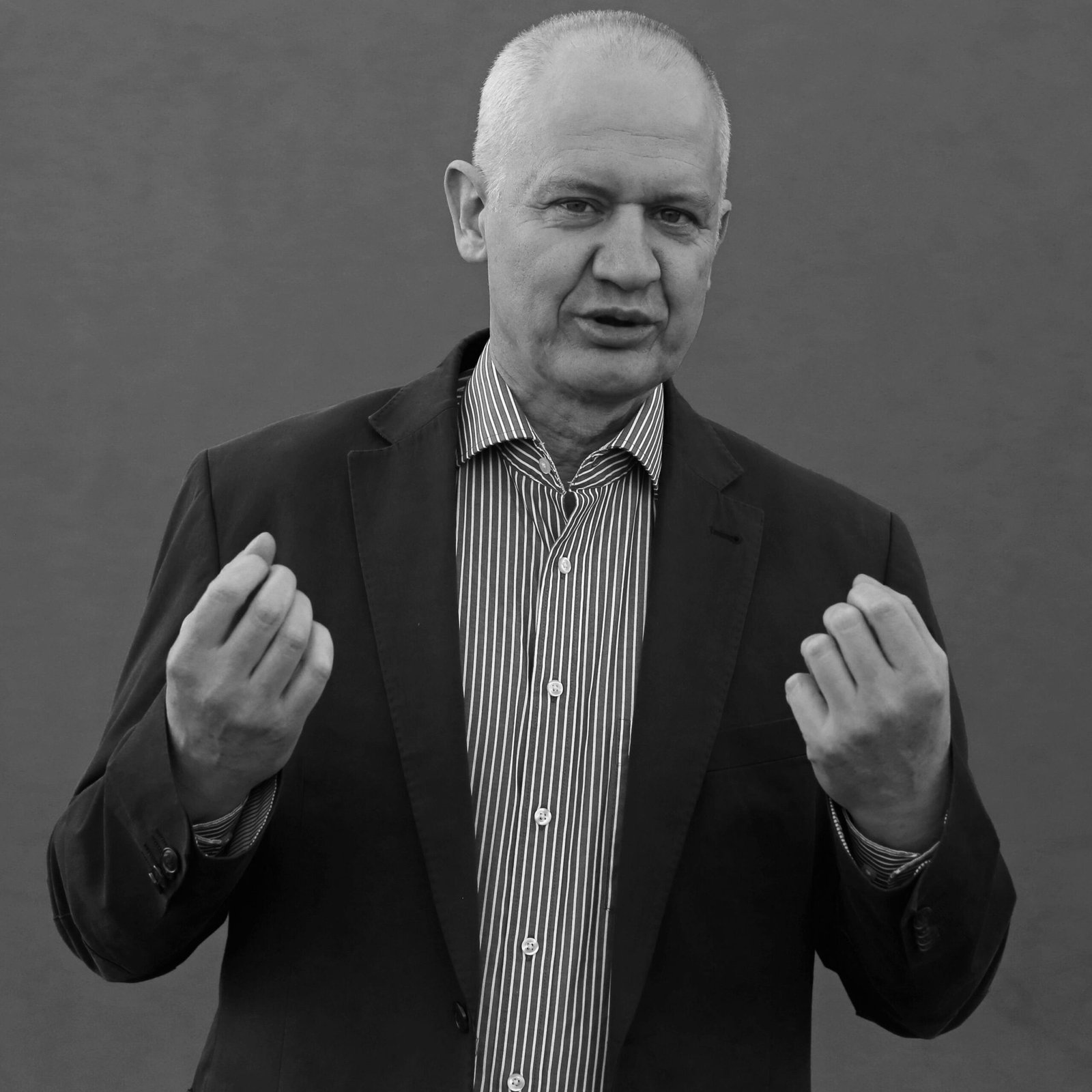 Senior businessman in suit jacket making a gesture, in black and white.